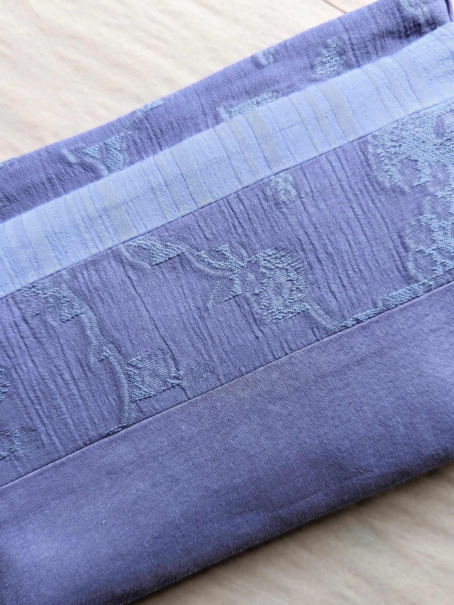 Close up picture showing the detail of the fabrics. Each has a different texture. One has a floral pattern woven into into, one is smooth with a twill weave and one, a slightly lighter shade, has unequal stripes woven in running vertically.