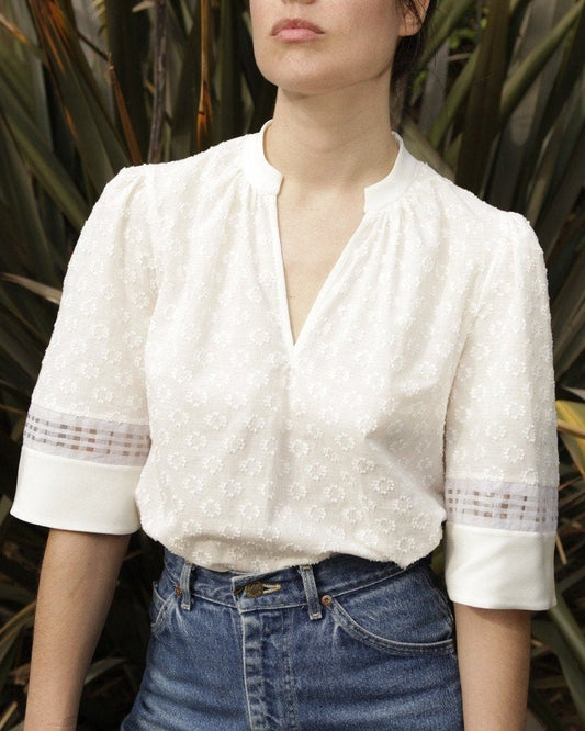The shirt has a rounded neckline with a deep v cutaway. The collar is made from white silk crepe and the same fabric is used to bind the deep v. The fabric is delicately gathered into the collar at the front to add a little shaping to the chest.