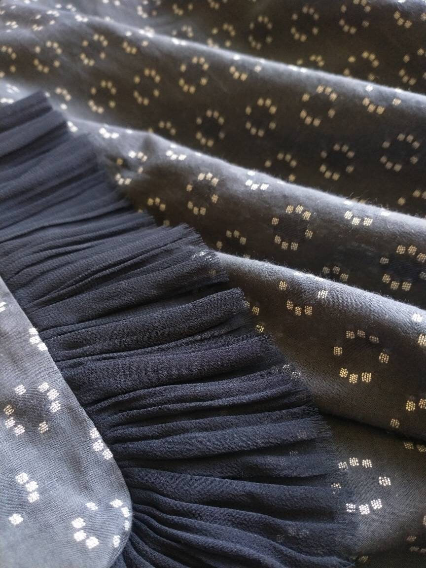 The Frida top is shown really close up, lying in folds to show the softness of the cotton fabric and the delicate pleating of the sleeve detail. The sheer chiffon fabric is unhemmed and frayed to create a delicate finish at the edge of the sleeve.